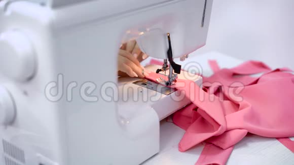 在裁缝室里用缝纫机工作的女工的手粉布缝合工艺视频的预览图