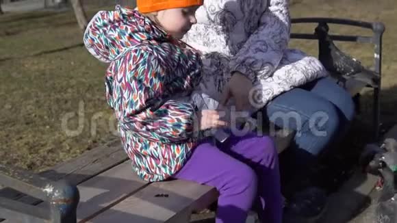 在寒冷的日子里年轻的女人和小女孩用葵花籽喂鸽子视频的预览图