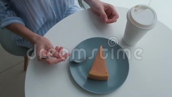 咖啡馆里的女人喝着热拿铁吃着芝士蛋糕视频的预览图