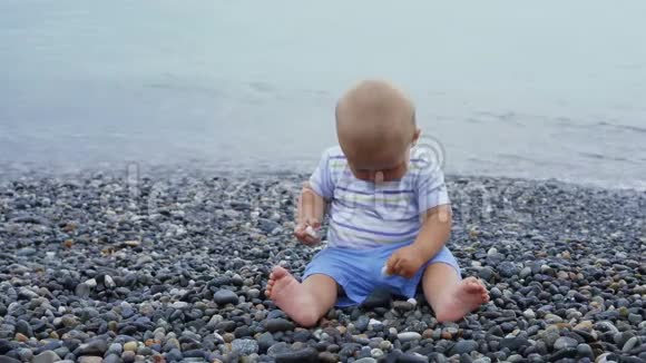 新生儿男孩在风和日丽的海边玩石头视频的预览图