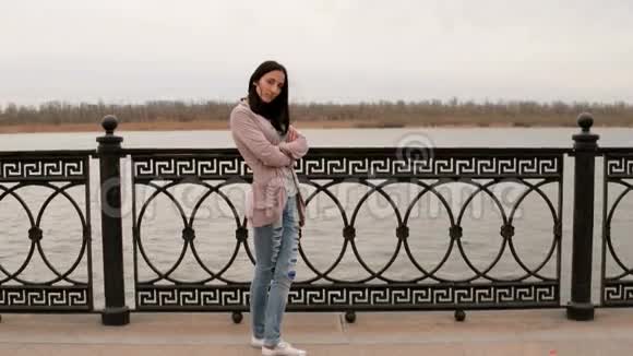 秋高气爽的女人站在河堤的金属栅栏前看着4K的风景视频的预览图