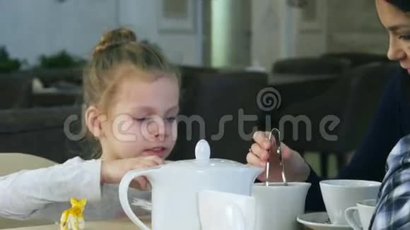 金发可爱的女孩试图把糖放在她的茶里她妈妈帮助她视频的预览图