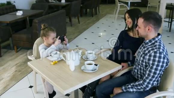 小现代女孩在咖啡馆里为她可爱的父母拍照视频的预览图