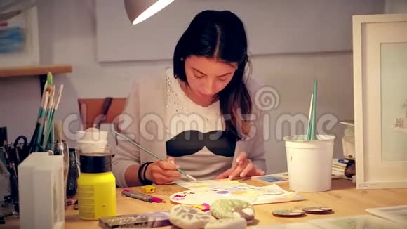 青年妇女在创作车间的办公桌上画艺术画视频的预览图