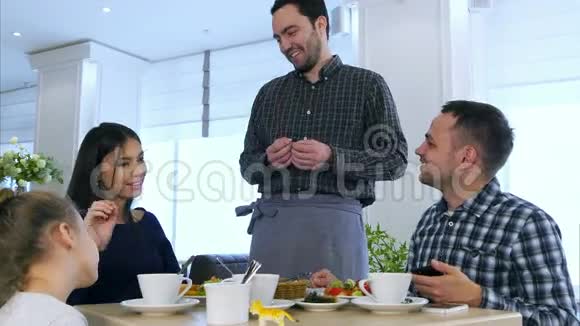 愉快的服务员与游客交谈年轻友好的家庭在餐厅吃饭视频的预览图