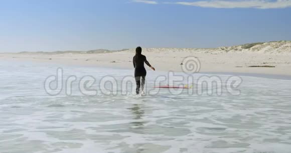 女人朝大海上的冲浪板跑去视频的预览图