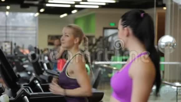 两个美女在健身俱乐部的跑步机上跑步视频的预览图