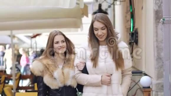 两个穿着毛茸茸外套的迷人女孩在购物中心散步慢慢地视频的预览图