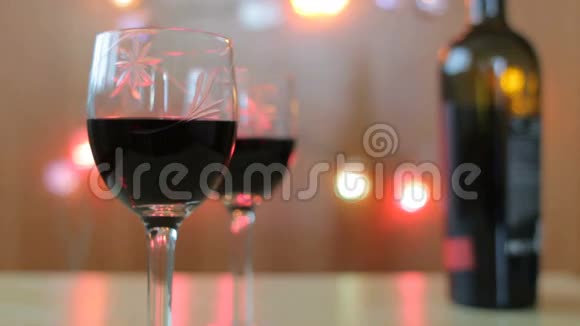 女人手拿一杯红酒有两个玻璃杯和酒瓶的桌子视频的预览图