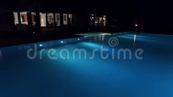 晚上在度假胜地的游泳池上空飞行视频的预览图