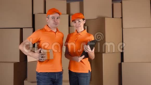 穿着橙色制服的快递员站在棕色的推车箱后面送货公司人员4K夹子视频的预览图