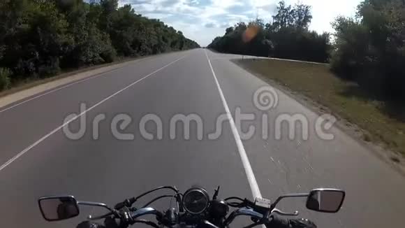 骑摩托车的人在森林之间的公路上行驶视频的预览图
