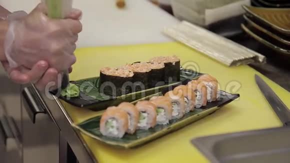 厨师在餐厅的厨房里用芥末装饰准备好的寿司卷视频的预览图