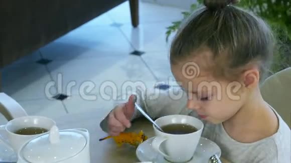 小金发女孩在父母忙着吃药片的时候用勺子喝茶视频的预览图