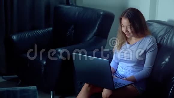可爱的亚洲女人晚上用笔记本电脑视频的预览图