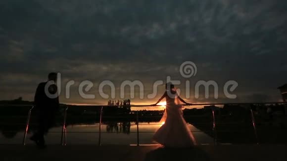 浪漫的恋人在黄昏拥抱背景是日落新婚夫妇爱情的温柔时刻视频的预览图