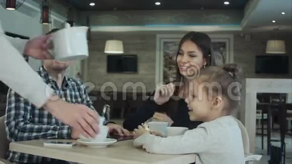 侍者在咖啡馆里给年轻的家人端茶和糖视频的预览图