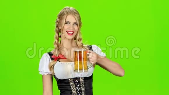 穿着巴伐利亚民族服装的女孩喝啤酒展示拇指绿色屏幕视频的预览图