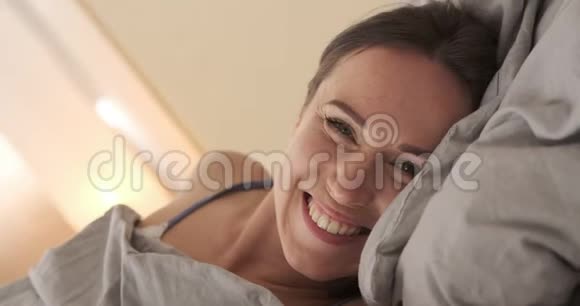 微笑的女人躺在床上被子视频的预览图