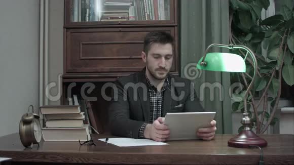 年轻人坐在他的学习桌前通过平板电脑打电话视频的预览图
