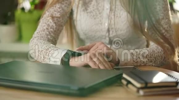 一个年轻女子的手特写镜头她把时钟放在智能手表上视频的预览图