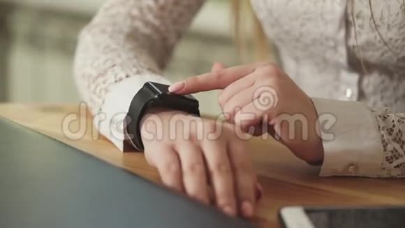 一个年轻女孩的手特写镜头她把时钟放在智能手表上视频的预览图