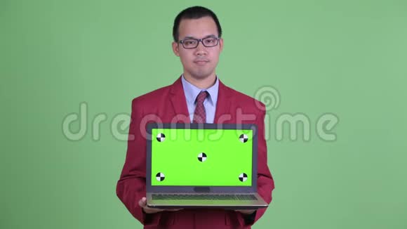 快乐的亚洲商人一边思考一边展示笔记本电脑视频的预览图