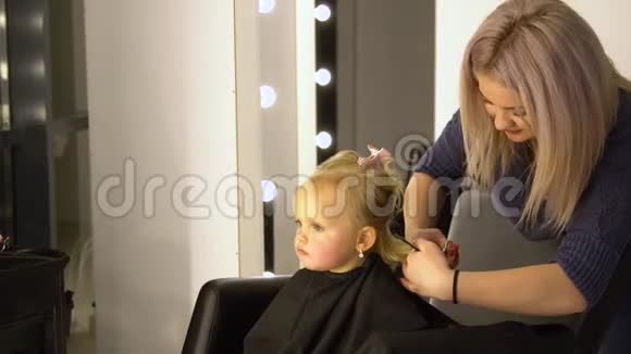 一个在美容院的小孩漂亮的女孩坐在椅子上理发师剪了她的头发孩子是视频的预览图