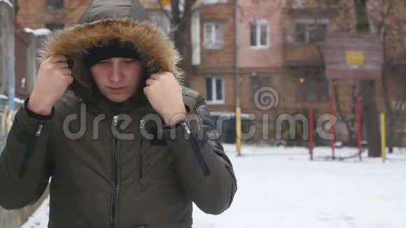 戴着黑帽子的年轻人在寒冷的冬天天气里暖手的肖像快关门户外活动视频的预览图