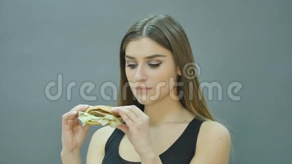 可爱的女孩在黑色背景下咬汉堡包视频的预览图