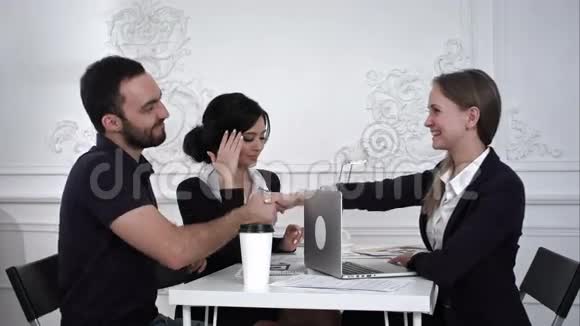 三位成功的商业伙伴在办公室里握手微笑视频的预览图