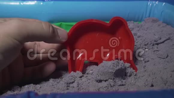 动能沙胖子他的手在沙堆里玩玩具视频的预览图