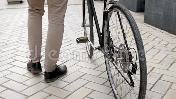低角度慢动作视频时尚年轻人步行在铺好的道路上与老式自行车视频的预览图