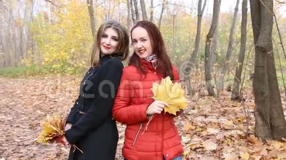 秋天公园里的两个年轻的女人拿着一束枫叶视频的预览图