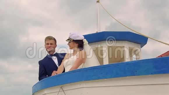 快乐的新娘和新郎在船上航行在年轻人的掌舵下视频的预览图