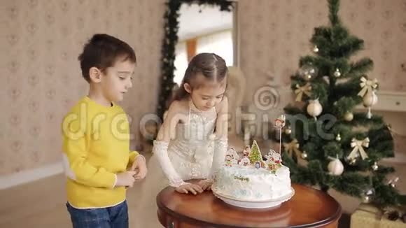 漂亮的小孩在宽敞的客厅里在圣诞树的背景蛋糕视频的预览图