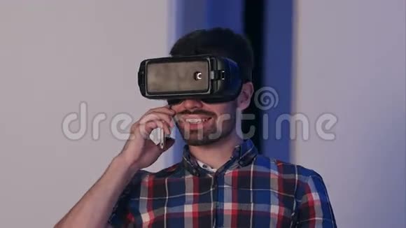 戴着虚拟现实眼镜的微笑男人在电话里交谈视频的预览图