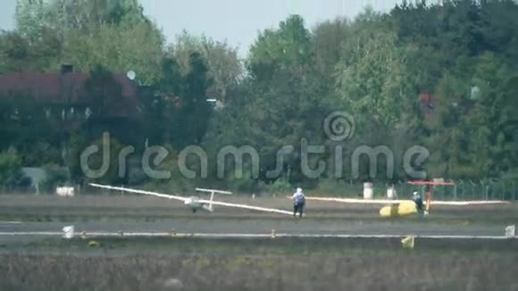 两名男子拖着一架滑翔机在跑道热霾外的地面上拍摄的电视镜头负担得起的业余航空视频的预览图