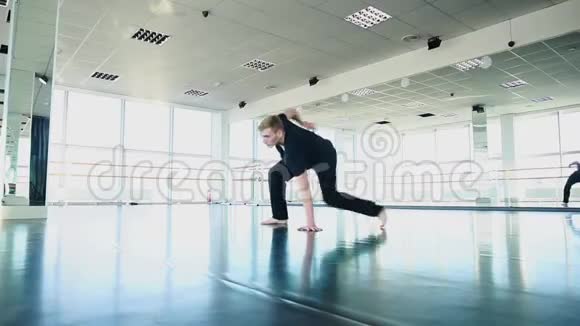 男舞者穿着黑色西装在工作室做扫荡视频的预览图