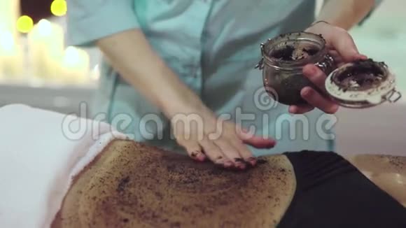 按摩师的手正在用咖啡擦洗女孩的特写镜头视频的预览图
