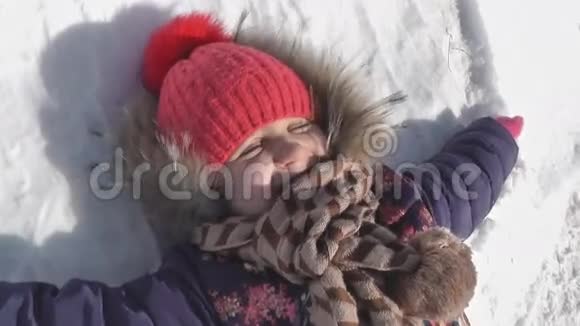 女孩躺在白雪皑皑的雪地上笑着快乐的冬天视频的预览图