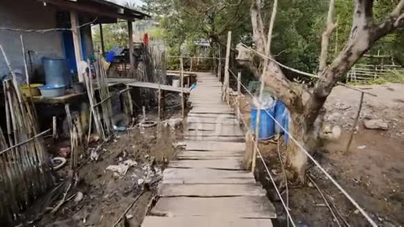 菲律宾贫民窟里穷人的房子沼泽地在高水位上用木板搭建的木桥鞋带上的衣服视频的预览图