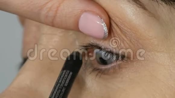 化妆师给蓝眼睛的中年妇女做眼妆年龄化妆特写肖像用刷子涂抹粉末视频的预览图