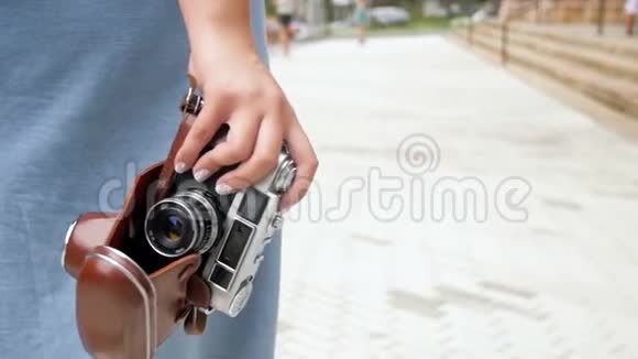 特写慢镜头年轻的旅游女孩在街上用老式摄像机行走视频的预览图