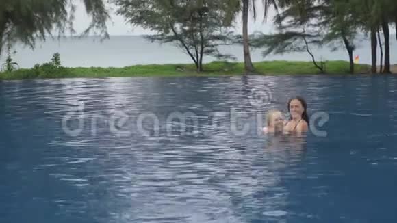 妈妈和一个两岁的女儿在海边的酒店游泳池里视频的预览图