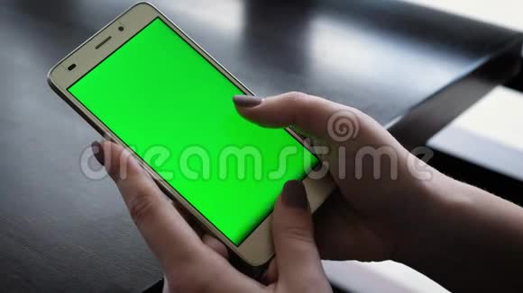 年轻女孩晚上拿着绿色屏幕的智能手机随意的生活方式在咖啡馆里视频的预览图