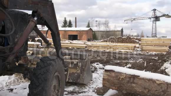 锯木厂的挖掘机堆放着覆盖着雪的木材材料视频的预览图