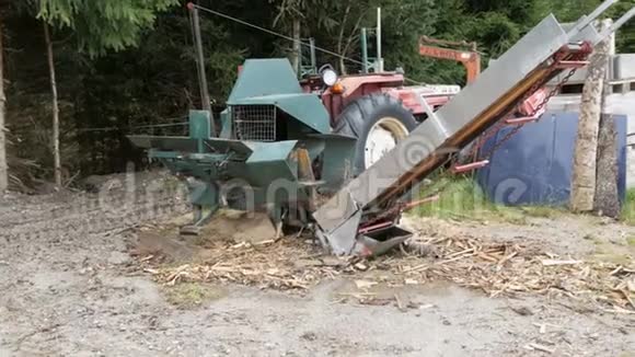 村里的小锯木厂一台拖拉机和一个锯架在树林里旁边是切割和包装的原木视频的预览图