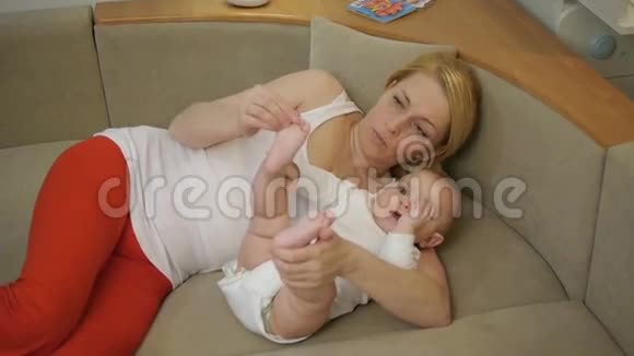 40岁的母亲躺在沙发上抱着一个微笑的婴儿视频的预览图