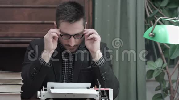 年轻作家戴着眼镜搓着手开始用红色老式打字机打字视频的预览图